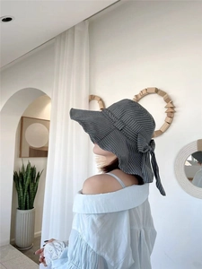 Detail of dark grey sun hat featuring white vertical stripes and back bow decoration