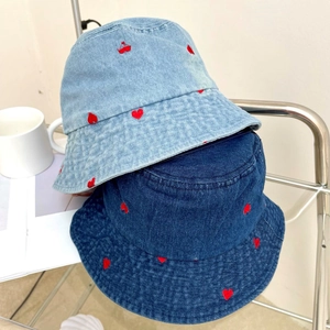 Detail of denim bucket hats with red heart and cherry embroidery on light and dark wash fabric