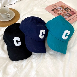 Three embroidered baseball caps in black, navy and blue on a minimalist white fabric