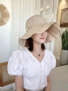 Detail of light beige striped sun hat with matching woven trim on a female model