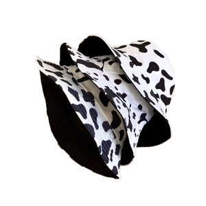 Chapeaux bob à imprimé vache noir et blanc empilés sur un fond blanc avec doublure