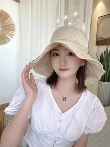 Detail of beige striped sun hat with woven trim and wide brim for UV protection