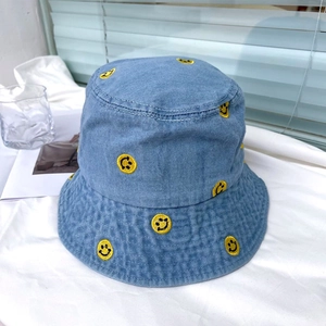 Close-up of yellow embroidered smiley faces on a blue denim bucket hat material