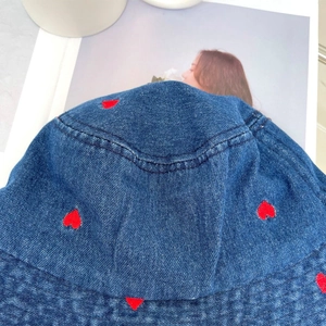 Close-up of red heart embroidery on navy blue denim bucket hat with twill texture