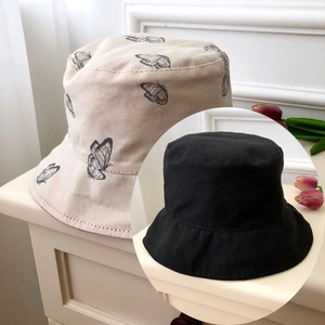 Detail of reversible bucket hats in black and beige with butterfly pattern embroidery