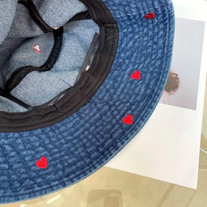 Close-up of blue denim bucket hat with red heart embroidery and black sweatband