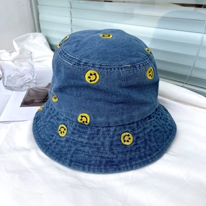 Detailed close-up of yellow smile embroidery on blue denim bucket hat fabric texture