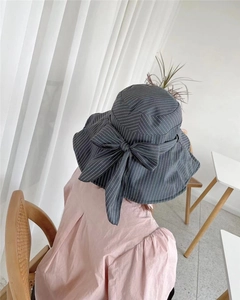 Detail of grey wide-brim sun hat with vertical stripes and large back bow decoration