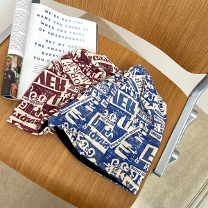 Dettaglio di berretti alla moda con stampa di giornale in rosso e blu su sedia in legno