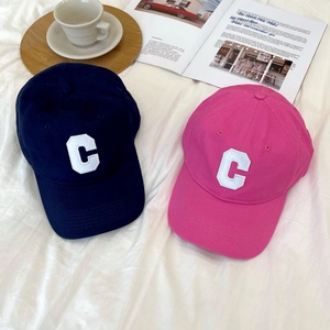 Detailed flat lay of navy and pink cotton baseball caps with embroidered C on fabric