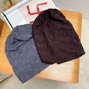 Set aus grauen und braunen Strickmützen mit Wellenstruktur auf einer Holzoberfläche