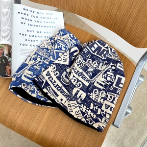 Dettaglio di berretti in maglia con stampa di giornale vintage in blu e crema su legno