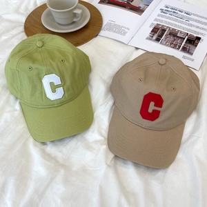 Close-up of embroidered C logo on cotton baseball caps in green and khaki colors