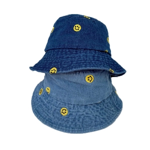 Deep and light blue denim bucket hats featuring yellow embroidered smiley face patterns