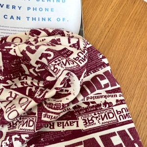 Dettaglio della stampa di giornale vintage sul turbante in cotone elasticizzato bordeaux