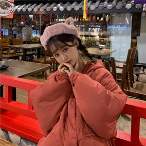 Close-up of cute pink plush cat-ear beret paired with thick warm red hooded winter jacket