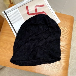Detailansicht der schwarzen Strickmütze mit Sternstruktur auf einem Holzhocker