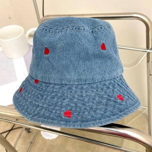 Detailed close-up of red heart embroidery on blue denim fabric of a bucket hat