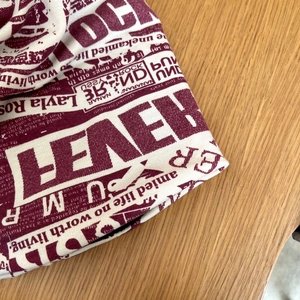 Dettaglio del berretto rosso bordeaux con stampa vintage su sfondo in legno
