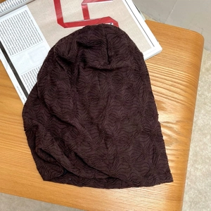 Nahaufnahme der dunkelbraunen Beanie mit Rautenmuster auf Holzgrund mit Magazin