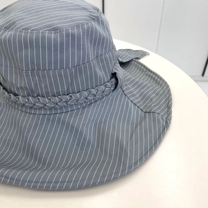 Detail of grey striped cotton sun hat featuring decorative woven band and elegant bow ribbon