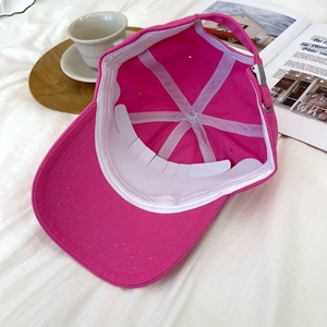 Detail of rose red cotton baseball cap interior with seam taping and metal buckle