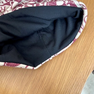 Dettaglio del berretto in maglia a doppio strato con stampa di lettere rosse e fodera