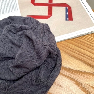 Nahaufnahme einer dunkelgrauen Beanie-Mütze mit plissierter Textur und weichem Strickgewebe