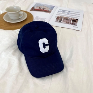 Close-up of navy cotton baseball cap with white embroidered C letter patch and twill texture