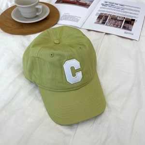 Detailed close-up of light green baseball cap featuring white embroidered C letter logo