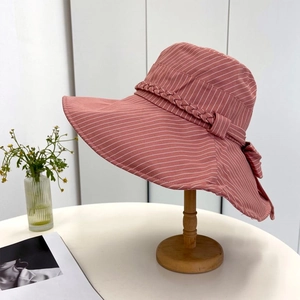 Detailed shot of pink striped sun hat with wide brim and woven ribbon on wooden stand