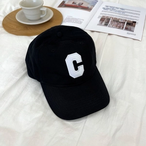 Detailed close-up of a black cotton baseball cap with white C embroidery on white fabric