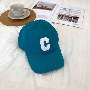 Blue cotton baseball cap with white towel-embroidered C on white wrinkled fabric