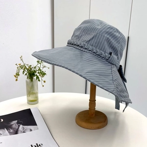 Detail of grey striped wide-brim sun hat featuring a knit band and bow decoration
