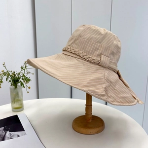 Detail of beige striped sun hat with wide brim, woven rope and fabric bow ornament