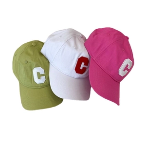 Three embroidered cotton baseball caps in green, white, and pink with large letter C design