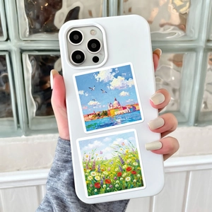 White smartphone case with scenic oil painting art prints held against a modern glass wall