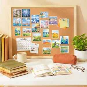 Close-up of impressionist landscape art stickers on a corkboard in a cozy office setup