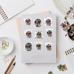 Macro shot of waterproof hamster stickers with phrases on a purple grid notebook