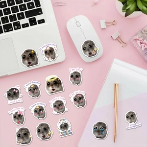 Detail shot of cute Sad Hamster meme stickers on a pink desk with office accessories