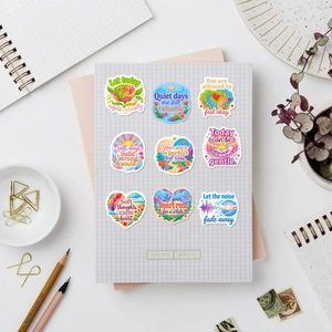 Detailed flat lay of 9 colorful waterproof mental health stickers on grid paper