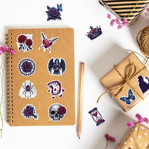 Vue macro de stickers gothiques avec crânes et roses sur un carnet en papier kraft