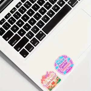 Inspirational mental health stickers with quotes applied on a white laptop surface