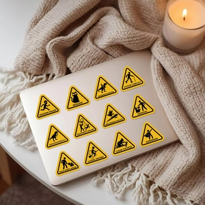Humorous yellow warning stickers set on a laptop with a cozy candle and blanket backdrop