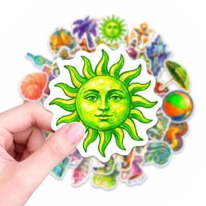 Macro detail of hand holding a cartoon green sun sticker from a summer travel pack