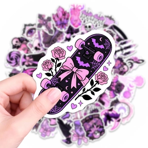 Close-up of a hand holding a purple gothic style waterproof sticker with a skateboard design