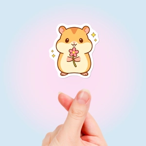 Gros plan d'un autocollant hamster mignon tenu par une main pour montrer les détails