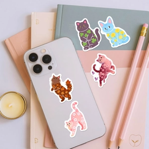 Detail of cute waterproof cat stickers with floral patterns on a white smartphone