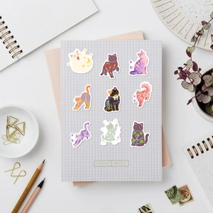 Detailed view of nine cute cat stickers with floral and moon motifs on grid paper