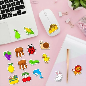 Waterproof cartoon animal and fruit stickers decorating a laptop on a pink desk